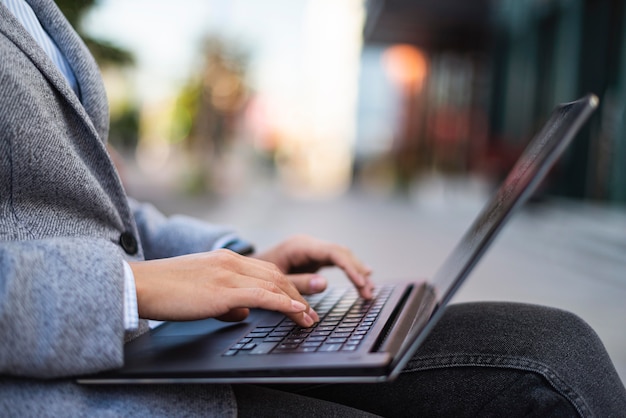 Vista lateral de uma empresária trabalhando em um laptop ao ar livre