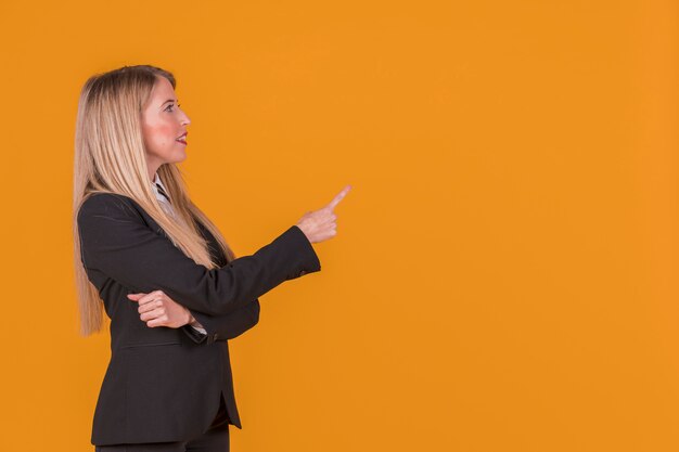 Vista lateral de uma jovem empresária apontando o dedo contra o pano de fundo