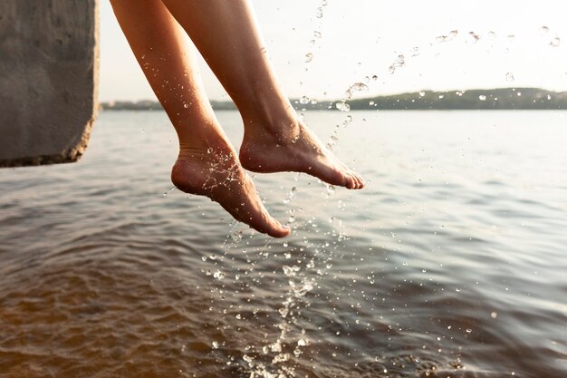 Vista lateral de uma mulher brincando com os pés no lago
