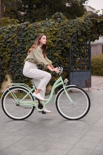 Vista lateral de uma mulher na cidade andando de bicicleta