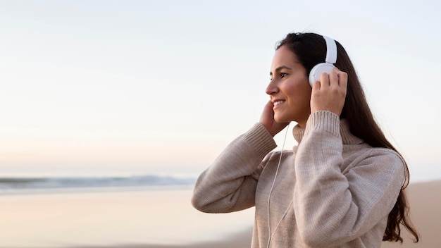 Vista lateral de uma mulher ouvindo música em fones de ouvido ao ar livre