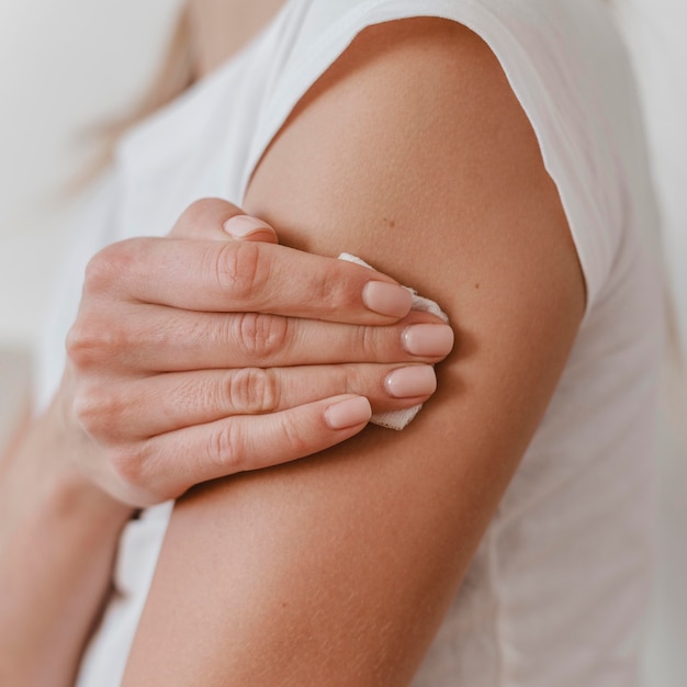 Vista lateral de uma mulher segurando o braço dela após tomar a vacina