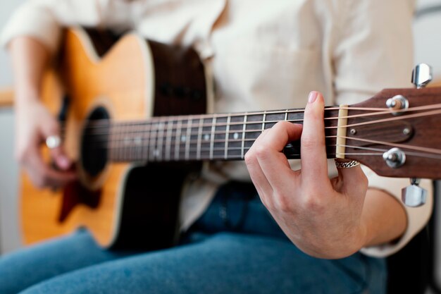 Vista lateral de uma musicista tocando violão