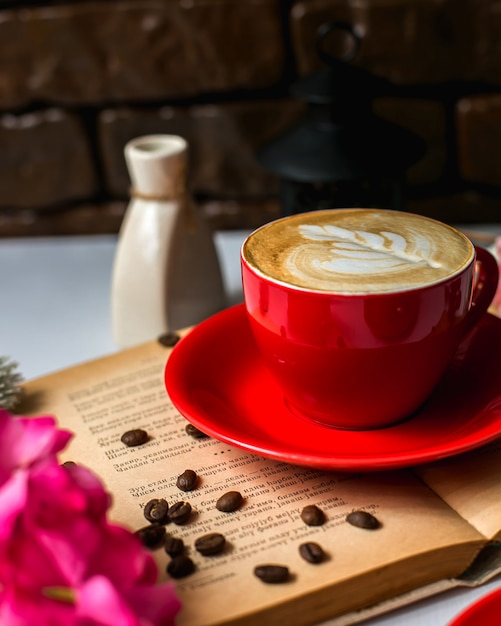 Vista lateral de uma xícara de café com leite e grãos de café na mesa