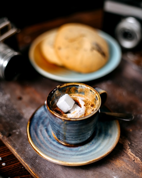 Vista lateral de uma xícara de café expresso com biscoitos no backgraund rústico