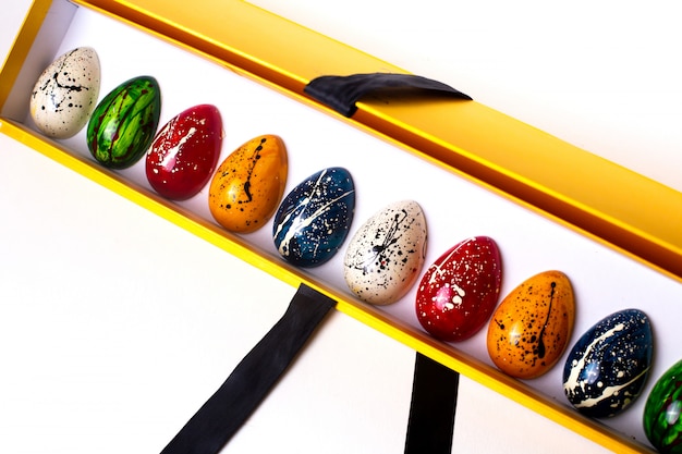Vista lateral decorada multi colorido ovos de chocolate em uma caixa aberta amarela