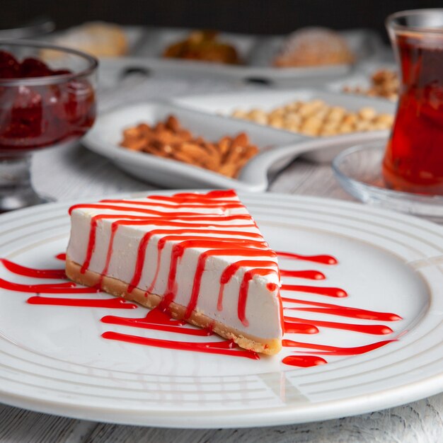 Vista lateral deliciosa sobremesa em prato com chá, nozes, geléia de frutas em fundo branco de madeira.