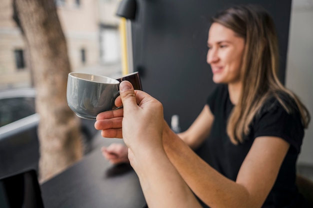 Vista lateral do barista feminino curtindo café