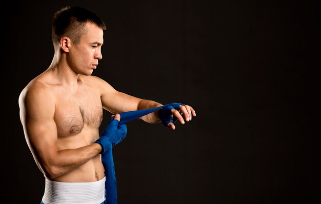 Vista lateral do boxer masculino, colocando proteção para as mãos, com espaço de cópia