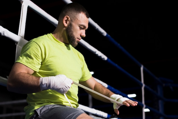 Vista lateral do boxer masculino em t-shirt, colocando proteção para as mãos, com espaço de cópia