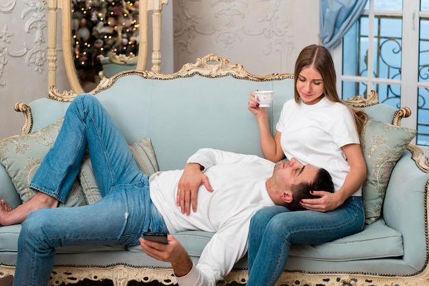 Vista lateral do casal abraçado no sofá com uma xícara de chá