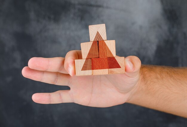 Vista lateral do conceito de estratégia de negócios. mão segurando a pirâmide do bloco de madeira.