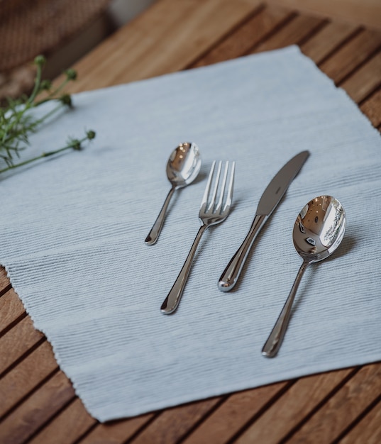 Foto grátis vista lateral do conjunto com colher garfo e faca na toalha de mesa em uma mesa de madeira
