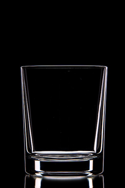Vista lateral do copo de vidro vazio na parede escura com espaço livre