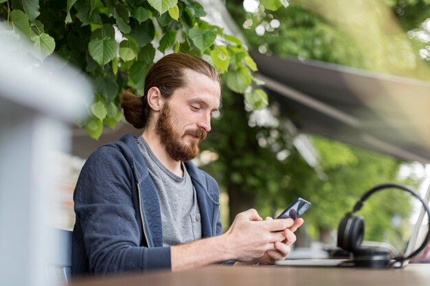 Foto grátis vista lateral do homem na cidade com smartphone e fones de ouvido