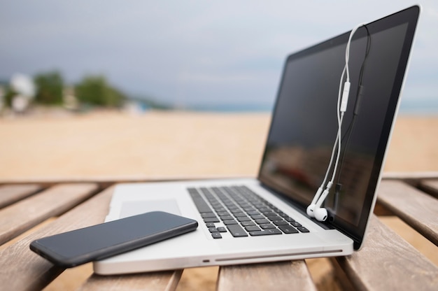 Foto grátis vista lateral do laptop na cadeira de praia com smartphone