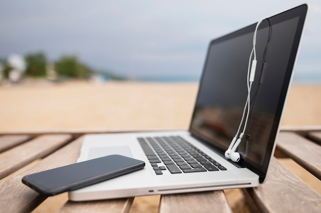 Vista lateral do laptop na cadeira de praia com smartphone