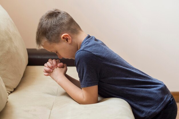Vista lateral do menino rezando