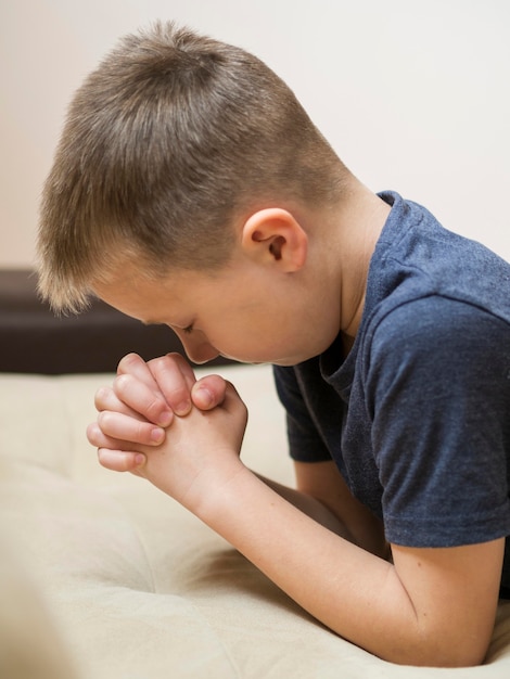 Vista lateral do menino rezando