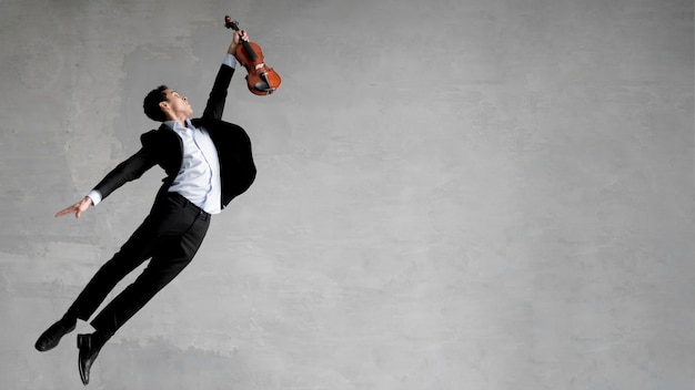 Vista lateral do músico masculino posando no ar enquanto segura o violino