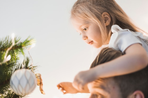 Foto grátis vista lateral do pai e da menina olhando a árvore de natal iluminada
