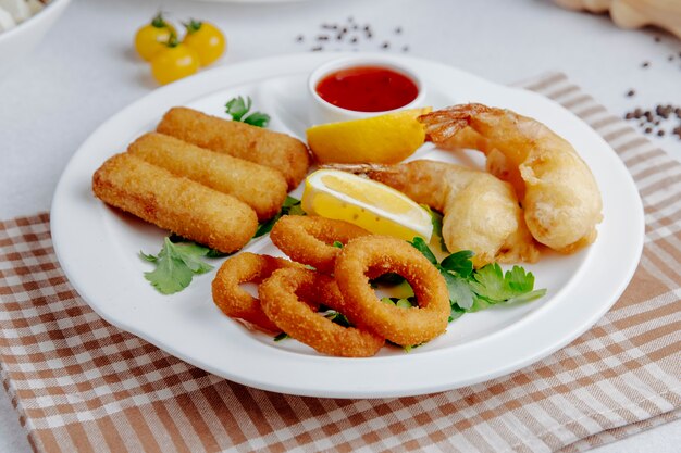 Vista lateral do tempura de lulas e camarões em um prato branco