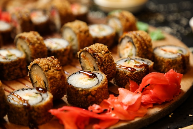 Vista lateral fritos rolos de sushi com wasabi e gengibre em um carrinho