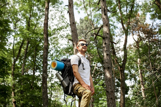 Vista lateral homem com mochila na floresta