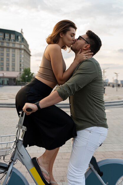 Vista lateral homem e mulher beijando na bicicleta