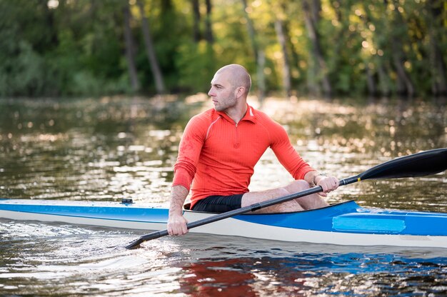 Vista lateral homem em canoa com remo