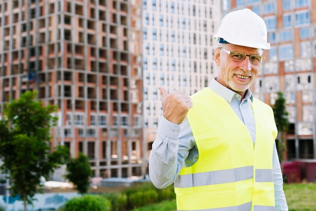 Vista lateral homem sorridente com colete e capacete