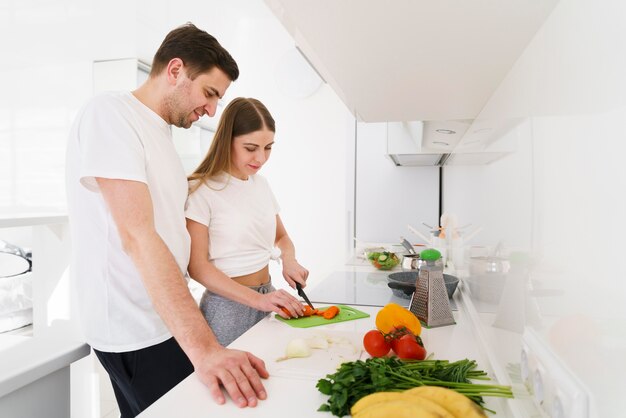 Vista lateral jovem casal na cozinha
