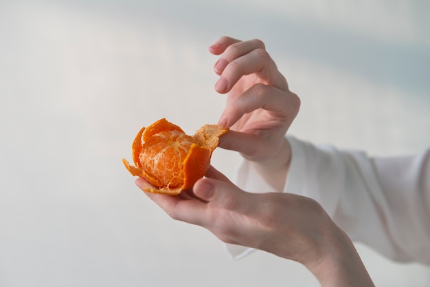 Vista lateral mãos descascando tangerina