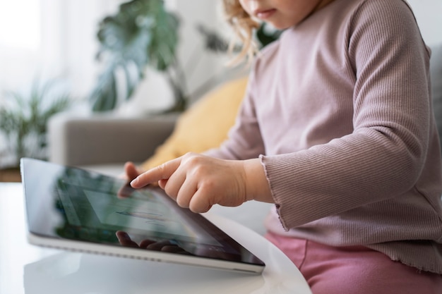 Vista lateral menina com tablet em casa