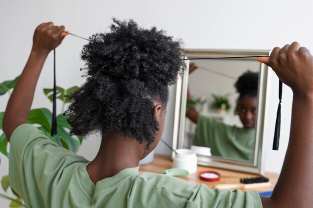 Vista lateral mulher arrumando o cabelo no espelho