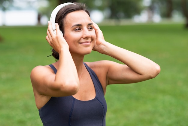 Vista lateral mulher com fones de ouvido ao ar livre