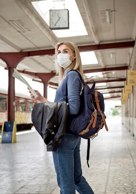 Vista lateral mulher com máscara na estação de trem