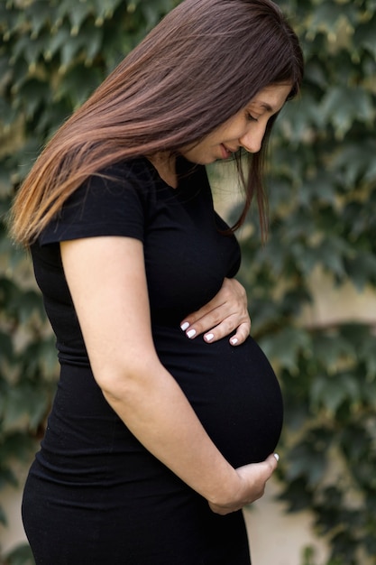 Foto grátis vista lateral mulher grávida de vestido preto ao ar livre