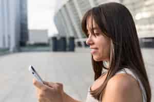 Foto grátis vista lateral mulher jovem e bonita sorrindo enquanto olha para o celular