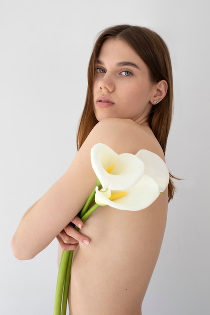 Vista lateral mulher nua posando com flores