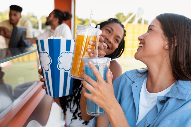 Vista lateral mulheres com bebidas e pipoca