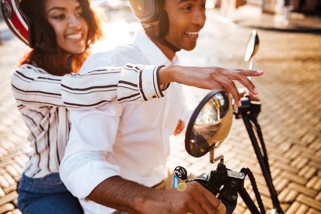 Foto grátis vista lateral recortada de passeios de casal africano satisfeito na moto moderna na rua