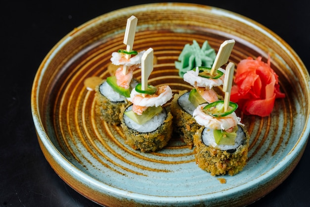 Vista lateral rolos de sushi frito com camarão com wasabi e gengibre em um prato