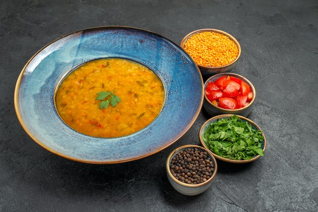 Vista lateral sopa de lentilha sopa de lentilha ao lado das tigelas de tomate especiarias ervas