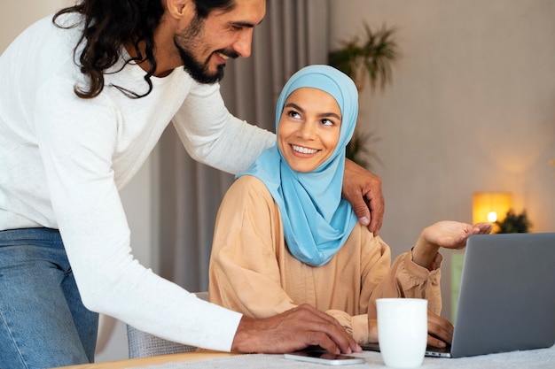Vista lateral sorridente casal islâmico com laptop