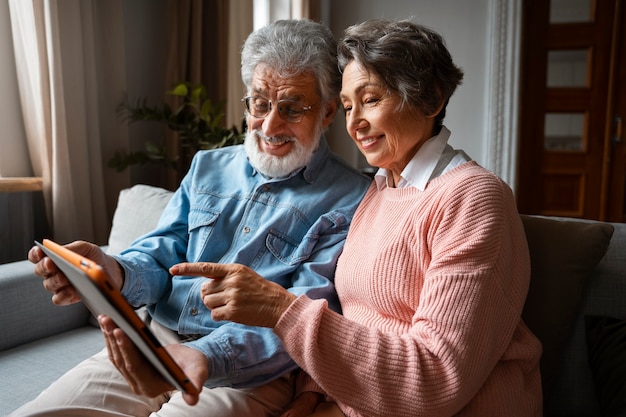 Vista lateral sorridente idosos com tablet