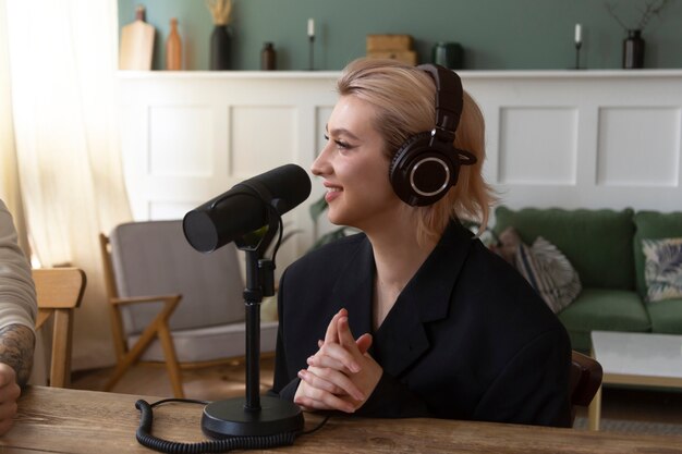 Vista lateral sorridente mulher gravando podcast