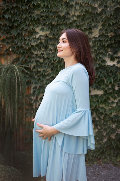 Vista lateral sorridente mulher grávida olhando para longe