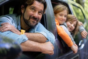 Vista lateral sorridente pai e filhos no carro
