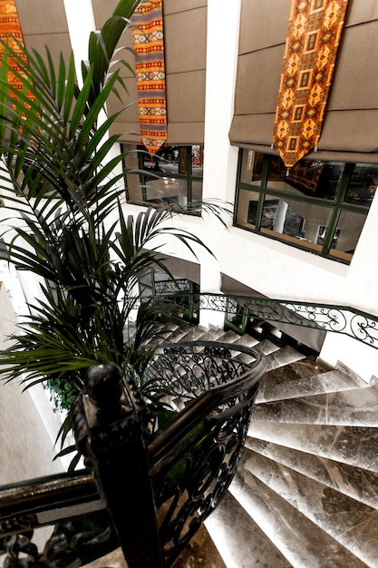Vista lateral superior das escadas do restaurante de mármore preto e janelas longas com persianas de tecido